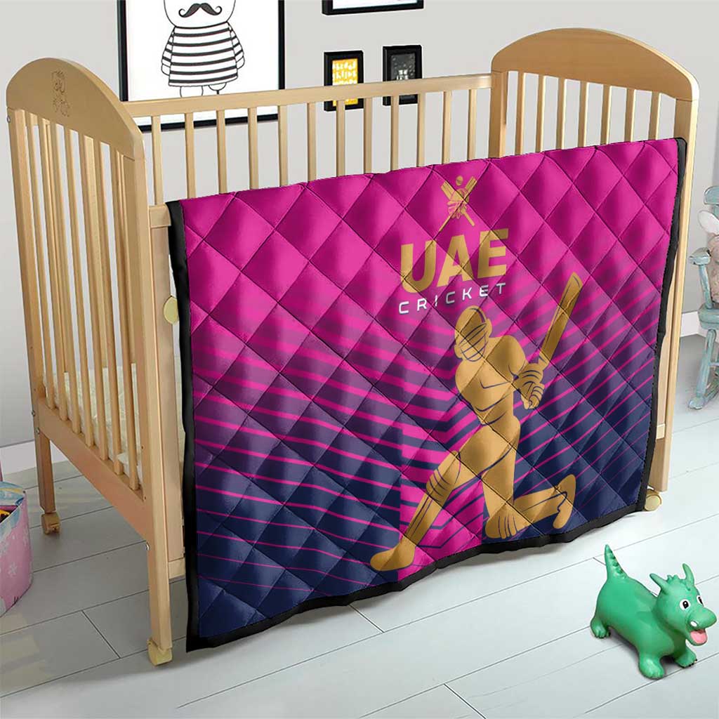 Pink UAE Cricket quilt in crib with gold “UAE CRICKET” logo and cricketer graphic