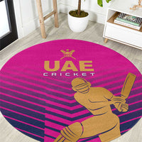 Pink round cricket carpet with gold UAE Cricket logo and player with bat graphic