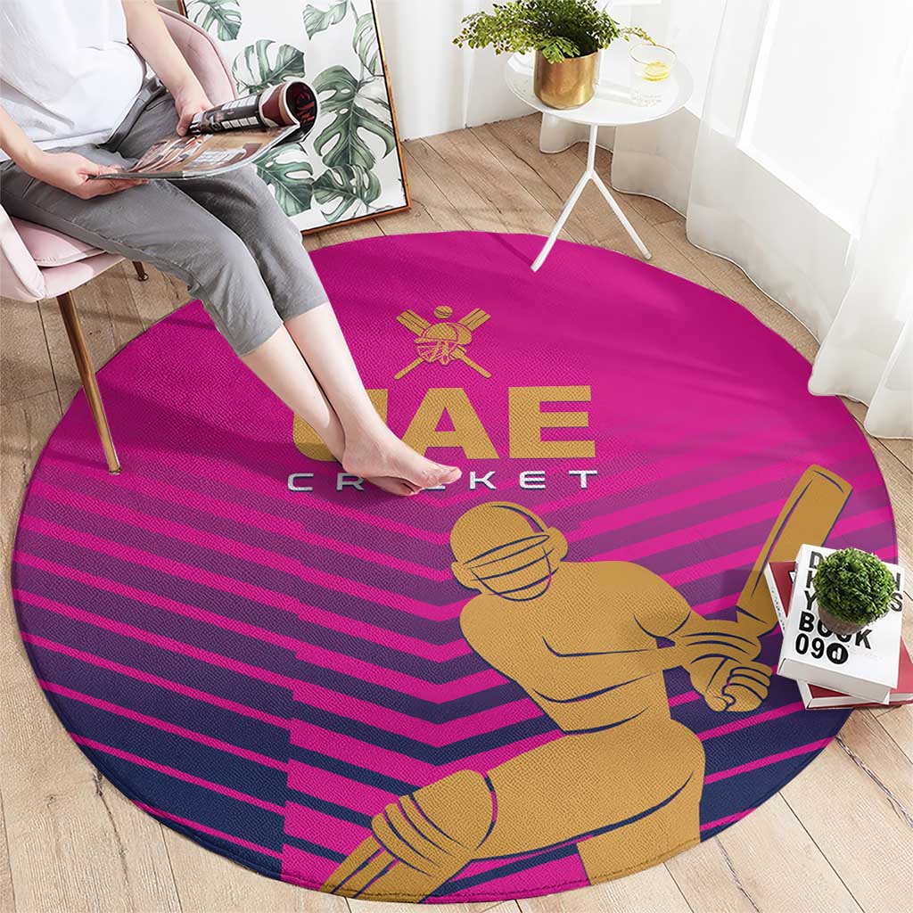 Pink round cricket carpet showing UAE Cricket logo, bat-and-ball player, and striped design