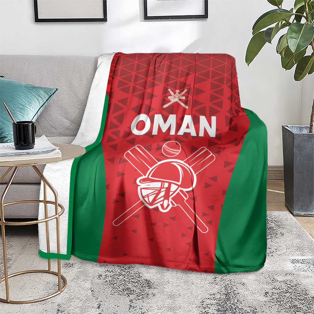 Oman cricket blanket spread on a rug, red and green with white “OMAN” team graphic
