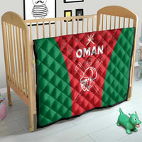 Oman cricket quilt on a crib, red center and green panels with white “OMAN” emblem