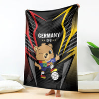 Black football blanket held up, Germany DFB text and cartoon mascot with soccer ball