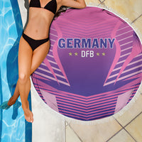 Round pink beach blanket with fringed edge, Germany DFB crest on purple graphic surface