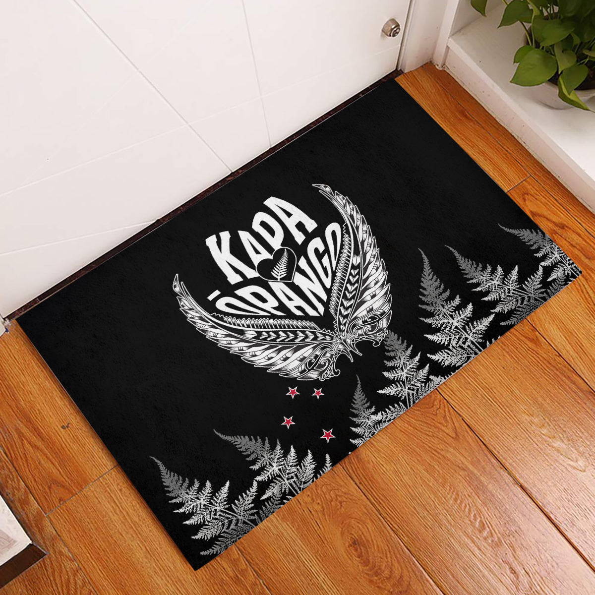 Black rubber doormat with Kapa Oranga emblem, silver fern wings and leaves