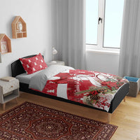 Red and white Christmas bedding set on bed, featuring bow and swan artwork