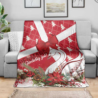 Red and white Christmas blanket draped on a sofa, showing bow, swan, and holiday florals