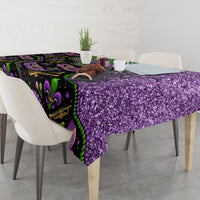 Mardi Gras tablecloth with purple glitter texture and green fleur-de-lis border, on dining table