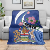 Blue Alberta crest blanket on gray sofa, showing wild rose and motto ribbons