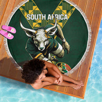 Green round beach blanket with fringe, South Africa bull graphic and geometric panels.