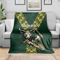 Green rugby blanket spread on a sofa with South Africa text, ox head, and yellow banner