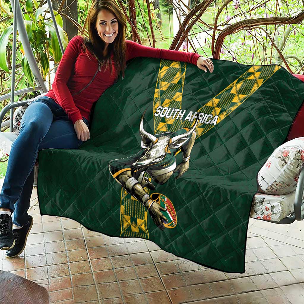 Green quilted South Africa rugby blanket with V stripe logo and horned mascot, draped on a couch