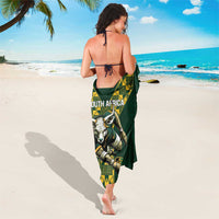 Green beach wrap sarong with yellow geometric panel and animal crest at center