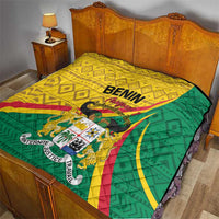 Benin quilt spread on a bed with green backing and yellow top featuring central emblem