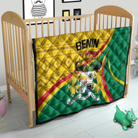 Benin quilt on a baby bed with yellow and green patterns, text, and central emblem