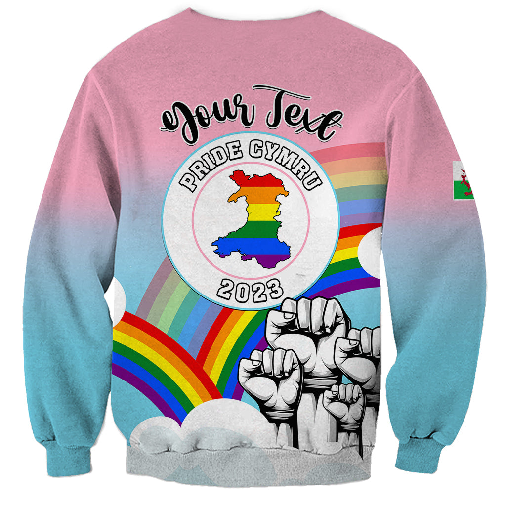 Unisex gradient pink-to-blue sweatshirt with circular Wales Pride emblem and fists graphic