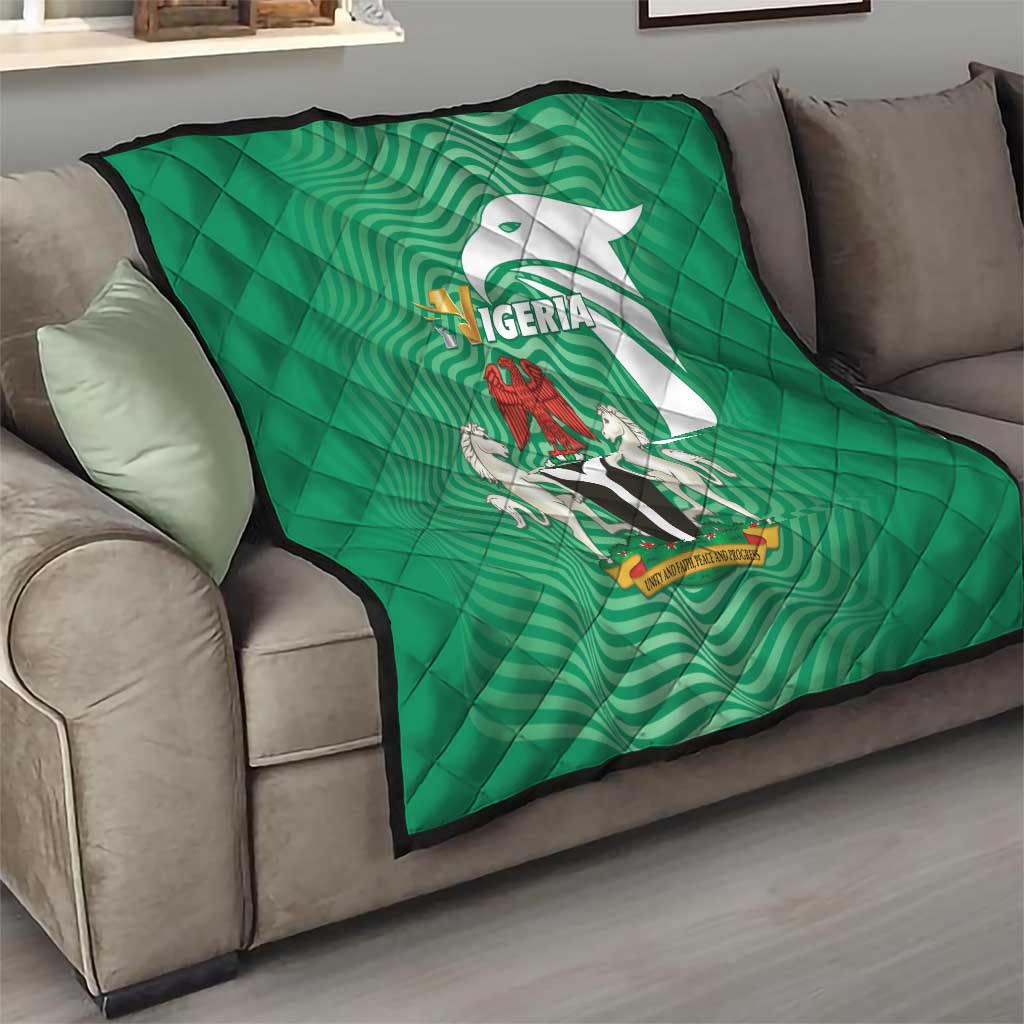 Green Nigeria quilt draped over a couch, quilted diamond pattern with emblem artwork
