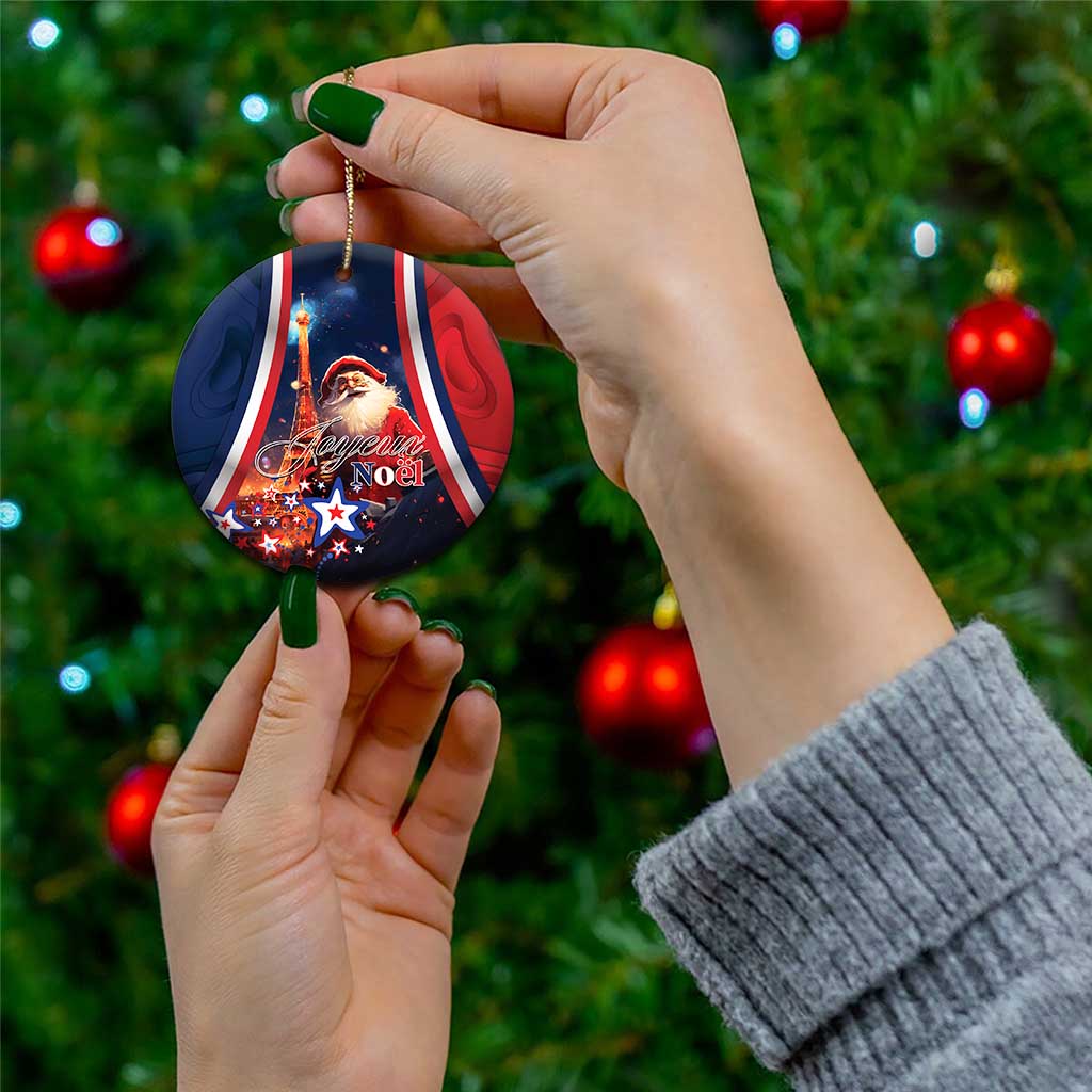 Blue round ceramic Christmas ornament with Santa and “Joyeux Noel”, held by hand