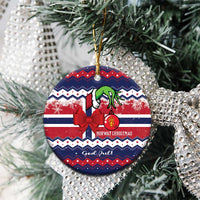 Round ceramic ornament on tree with red bow, green figure, "God Jul" and gold hanger