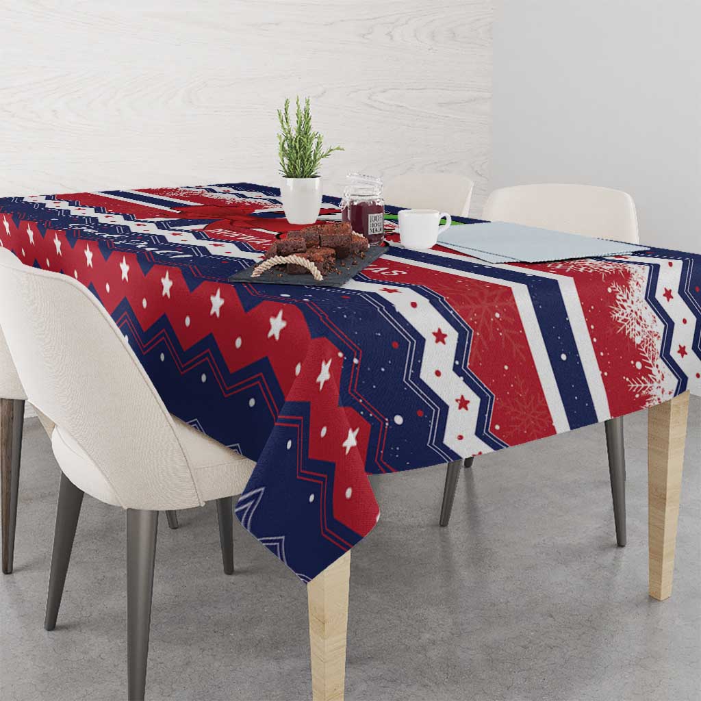 Christmas tablecloth draped over table edge in navy, red and white with stars and festive geometric pattern