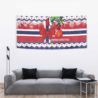 Blue Norway Christmas tapestry featuring a red ribbon bow, green figure, snowflake bands, and stripes