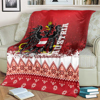 Red and white Christmas eagle blanket on couch, featuring crest, snowflakes, and diamond motifs
