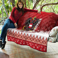 Red Christmas quilt draped over couch, eagle crest center, white snow band and zigzag trim