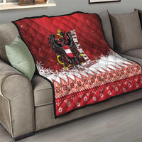 Red Christmas quilt on gray sofa, centered black and gold eagle crest with snowy geometric panel