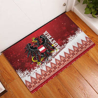 Red corner view Christmas eagle rubber doormat with black emblem, white snow, zigzag trim.