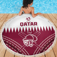 Round beach blanket with Qatar text and maroon cricket helmet emblem, fringed edge on deck