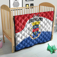 Red, white, and blue quilt blanket on a baby bed with Saint Barthelemy crest centerpiece