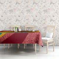 Red glitter-speckled tablecloth with Grenada-themed multicolor trim on tabletop