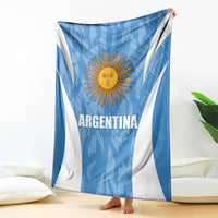 Argentina football blanket, blue with white V stripes and sun crest, spread on floor.