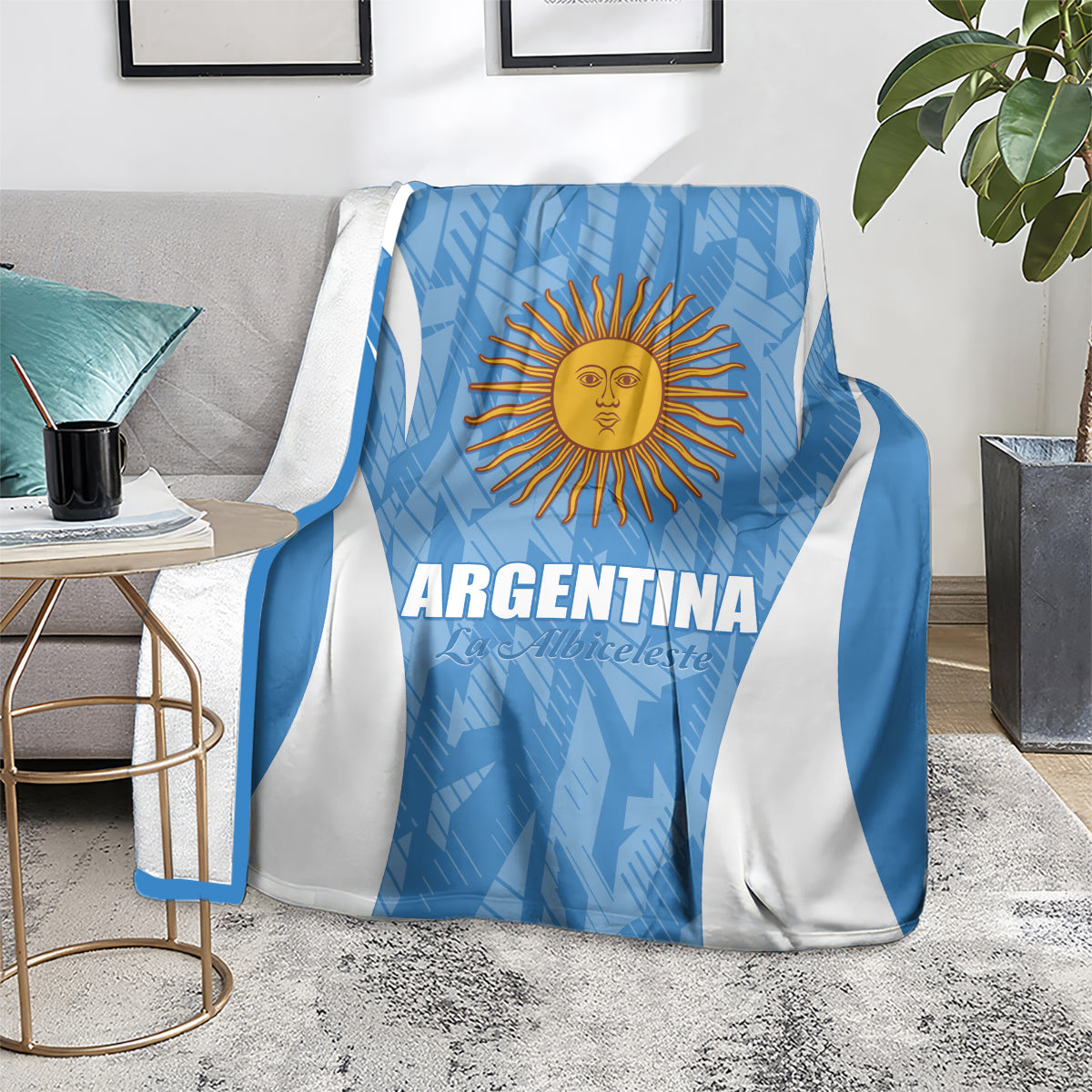 Argentina football blanket, blue with white V stripes and sun crest, draped on gray couch.