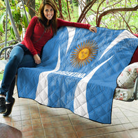 Argentina blue quilt blanket with sun emblem and white diagonal stripes, wrapped on sofa