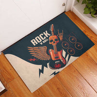 Rock-themed rubber doormat laid on floor, featuring orange guitar skull, wings, and speaker circles.