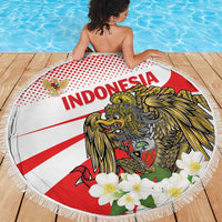 Round beach blanket with fringe showing Indonesia lion-and-eagle graphic and white flowers
