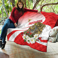 Red and white Indonesia quilt blanket with eagle and flower print, draped over couch