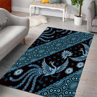 Rectangular blue area rug with batik motifs, peacock figure, and floral accents.