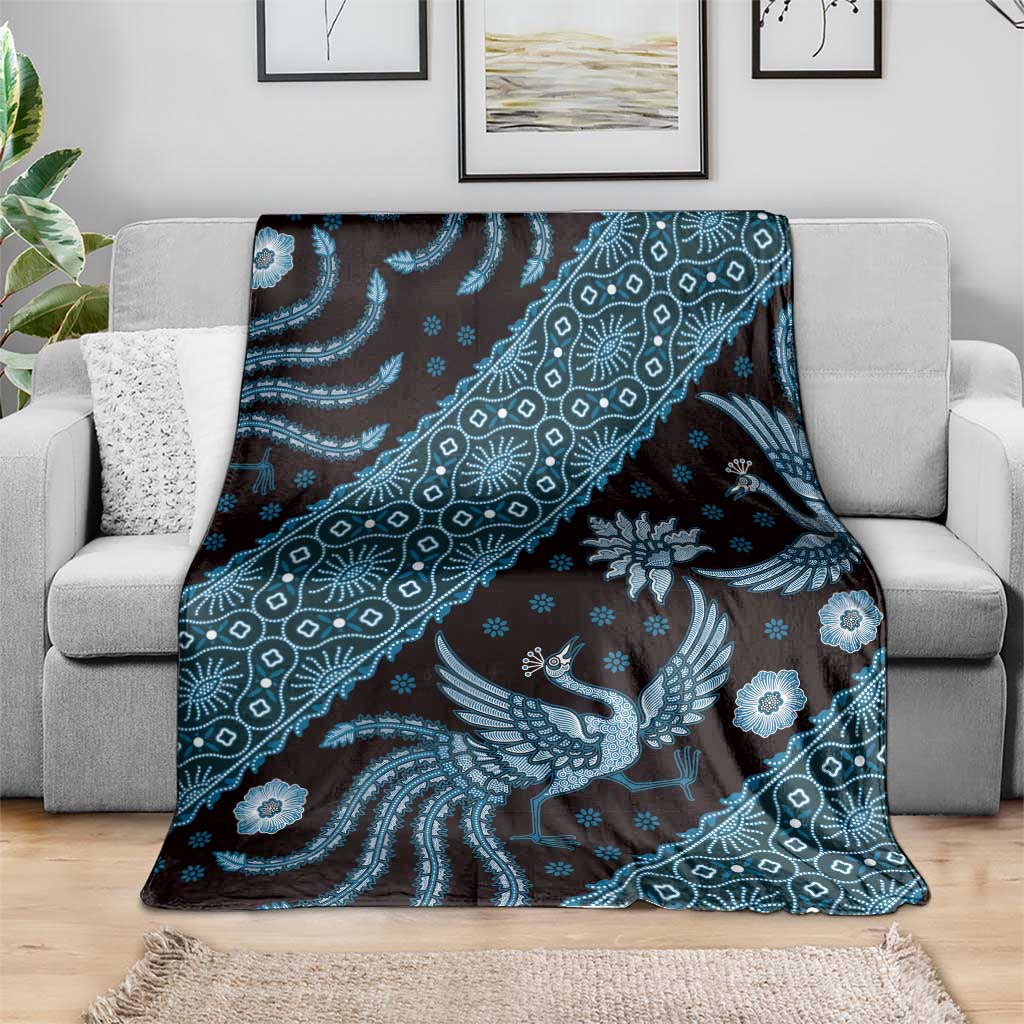 Blue batik-pattern blanket spread on gray sofa, large bird and floral medallion motifs