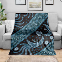 Blue batik-pattern blanket spread on gray sofa, large bird and floral medallion motifs