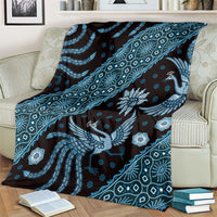 Blue batik-pattern blanket on striped couch, bird design and repeating geometric lines