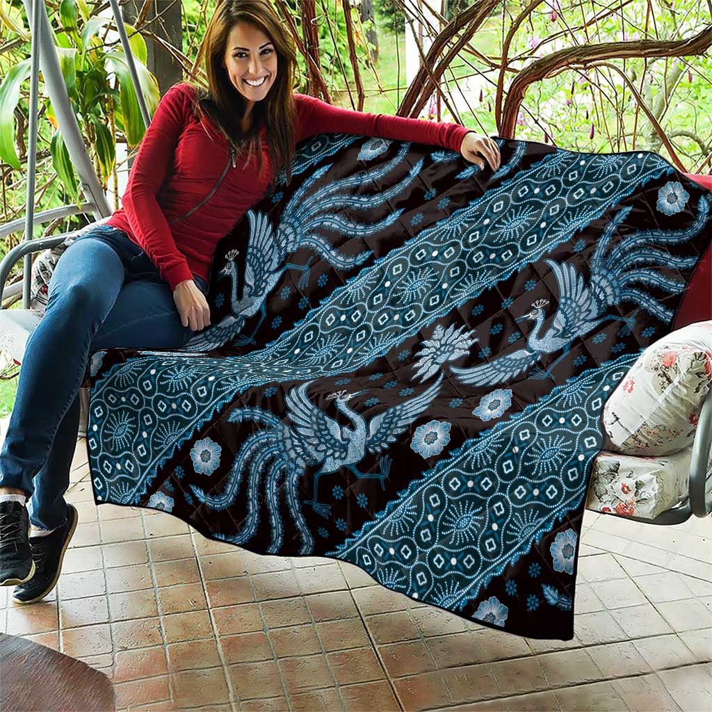 Blue batik pattern quilt spread out, featuring dragon silhouettes and floral shapes
