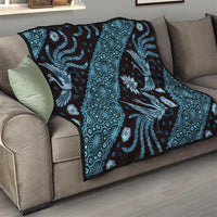 Blue batik pattern quilt draped on a sofa with dragon and diamond motifs