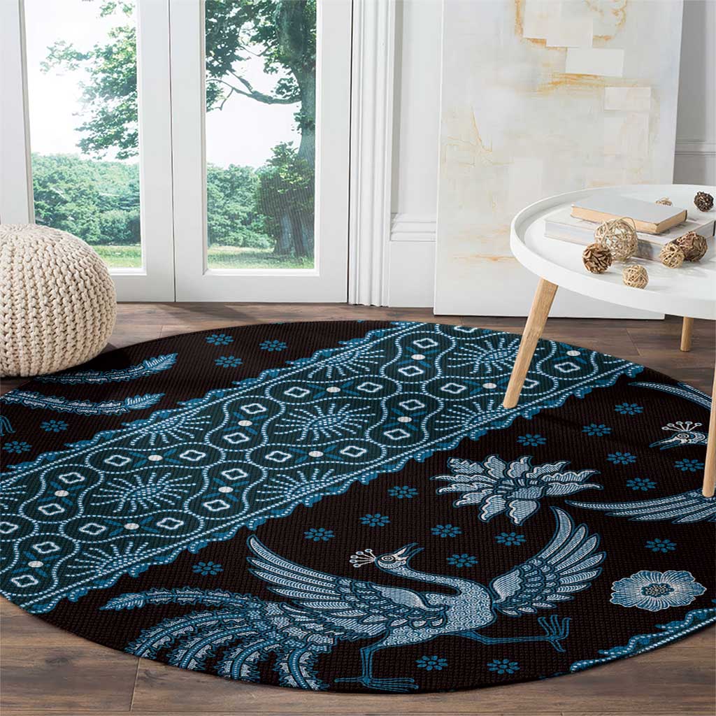 Round area rug with blue batik bird and diamond-dot geometric pattern on dark ground