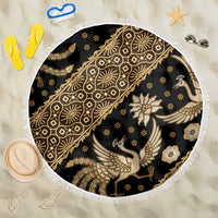 Round batik beach blanket with dark black base and gold floral bird motifs, white tassel fringe