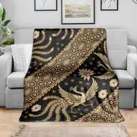 Batik throw blanket draped on sofa, dark base with gold bird and floral print