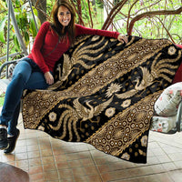 Decorative batik-style quilt with gold and cream animal motifs and geometric borders on dark cloth