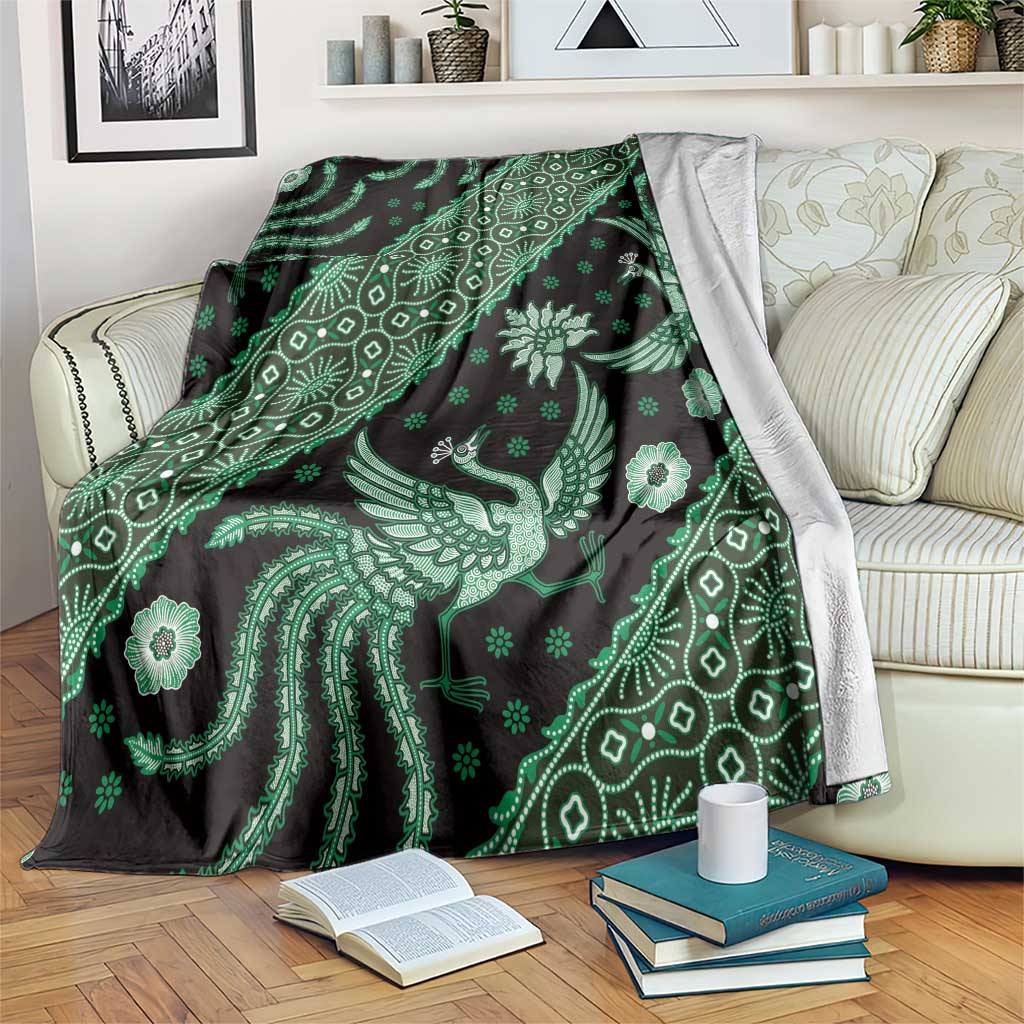 Green batik pattern throw blanket draped over couch, bird and floral motifs