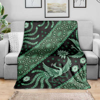 Green batik pattern blanket spread on gray sofa, bird and floral motifs