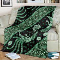 Green batik pattern throw blanket on cream sofa, bird and floral motifs